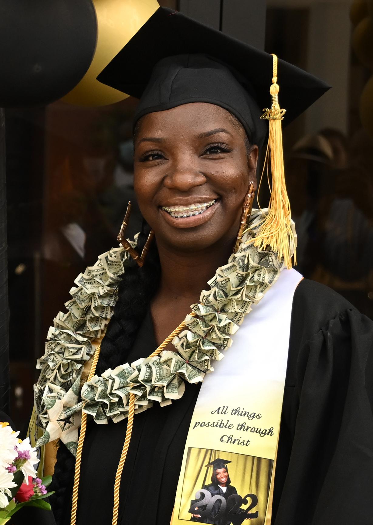 a graduate wears a necklace made of dollar bills