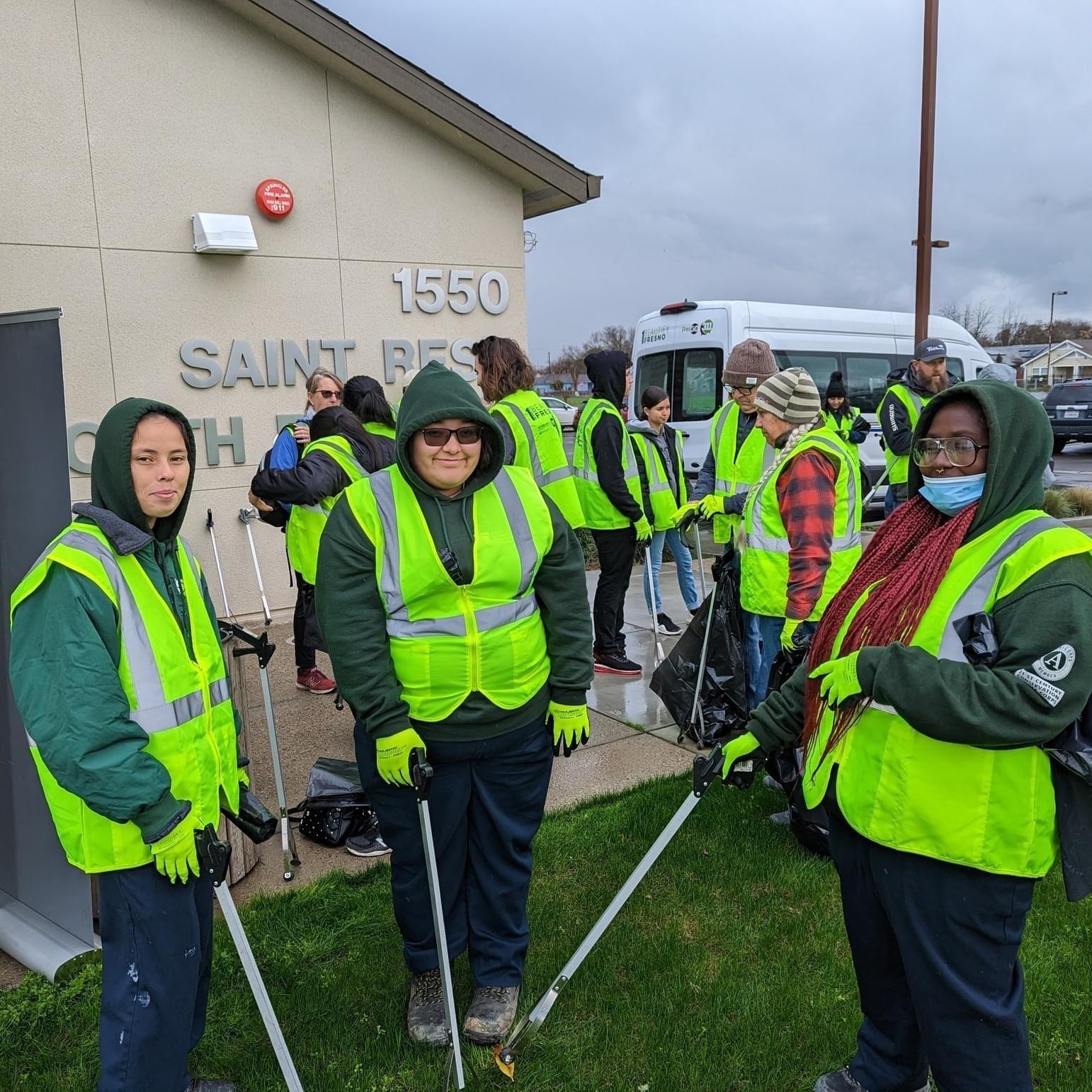 Photo of Aaliyah and other Fresno students wearing yellow vests and holding trash pickers before a cleanup event
