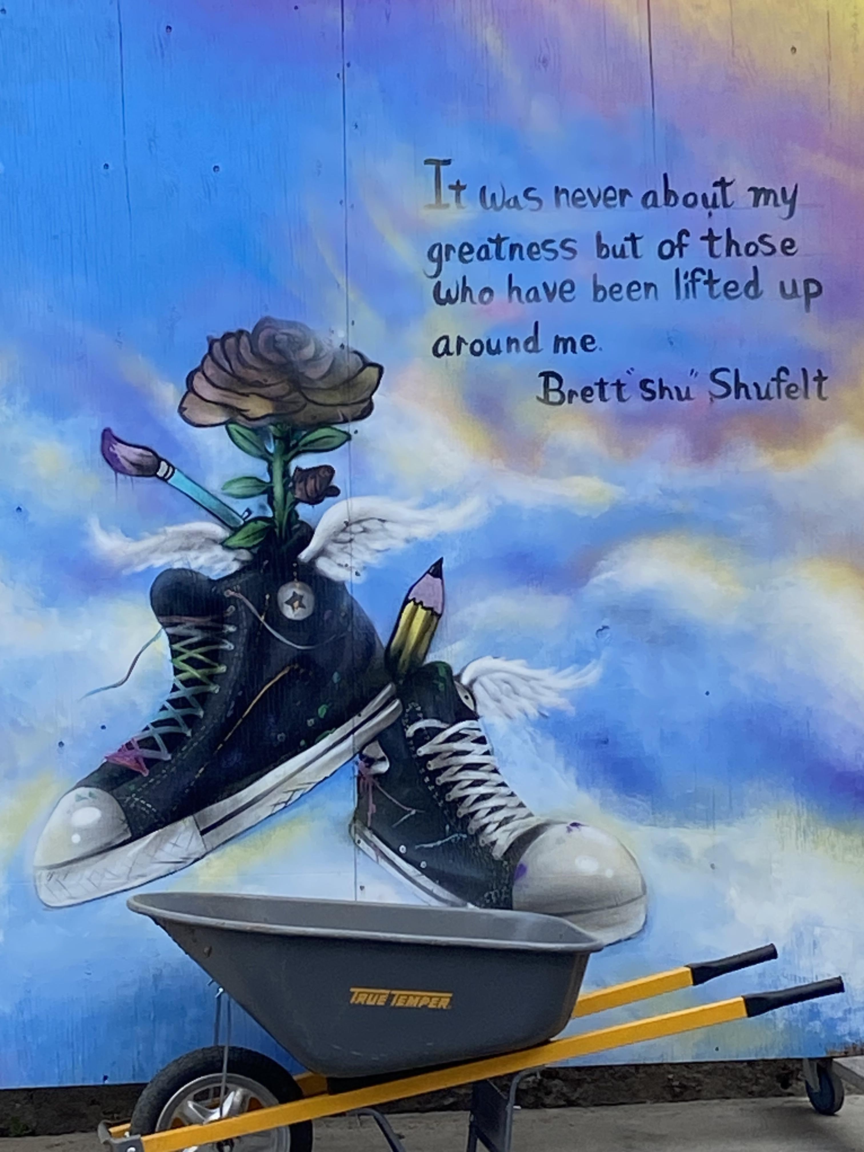 a photo of a painting displaying a pair of shoes and a quote