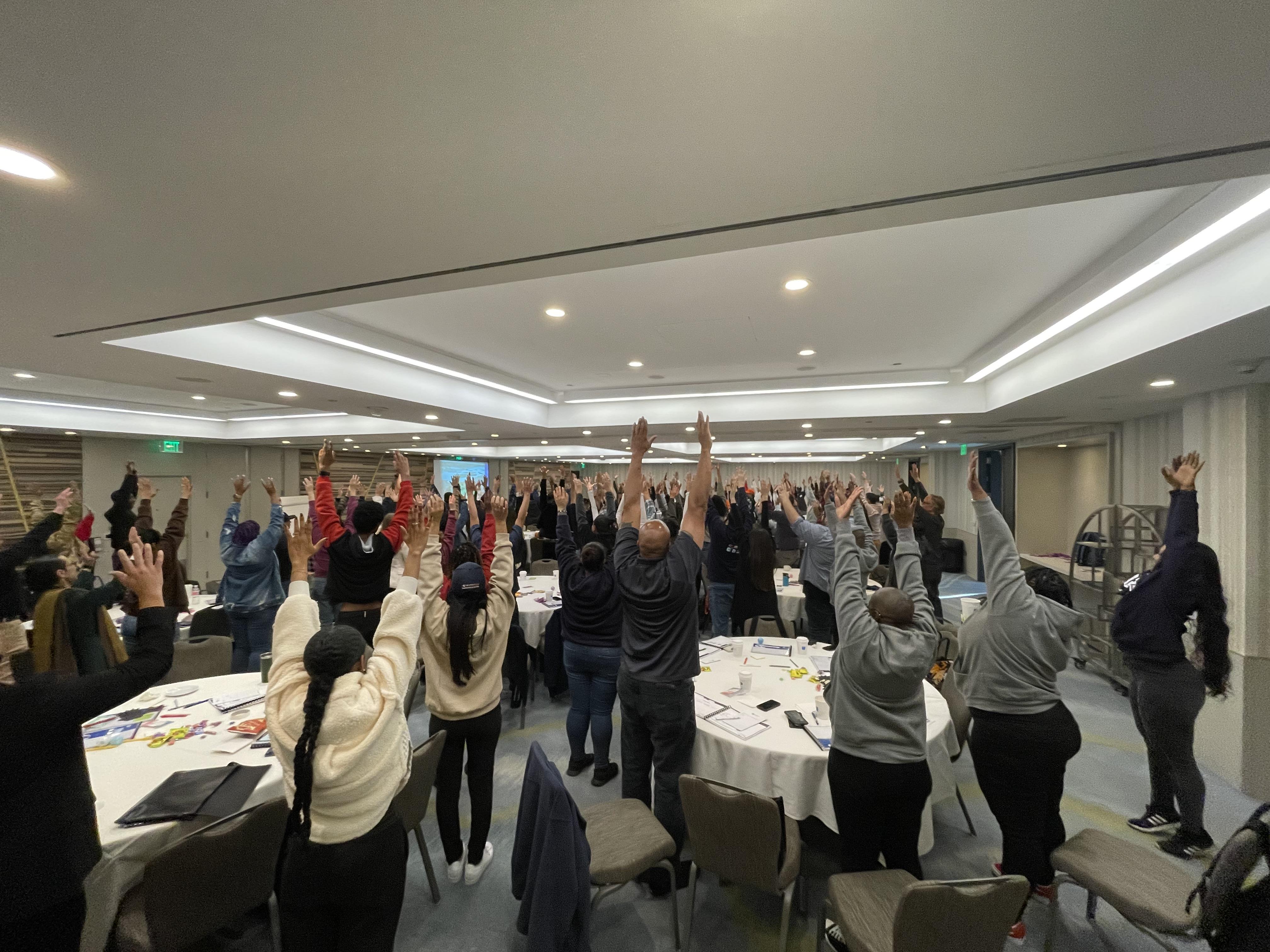 all staff with their hands up for a "Bar of Expectations" exercise